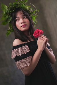 Portrait of beautiful woman wearing red rose