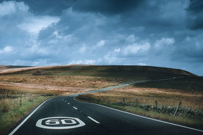 Road by field against sky