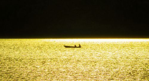 Scenic view of illuminated field on silhouette land against sky