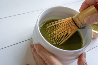 Cropped hand of woman holding bowl on table