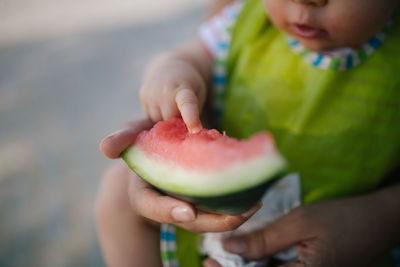 Midsection of girl with mother holding watermelon slice