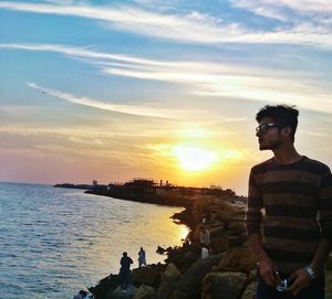 Man standing by sea against sky during sunset