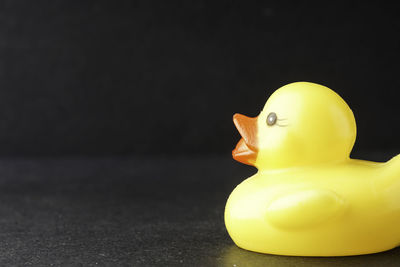 Close-up of yellow toy on table against black background