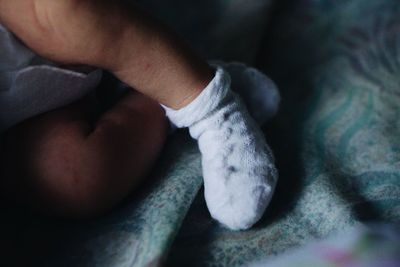 Cropped image of baby wearing socks while resting on bed