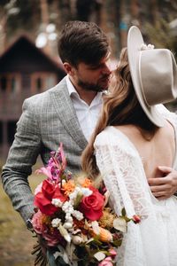 Couple with bouquet kissing outdoors