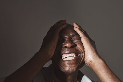 Elderly man laughing while covering face at studio