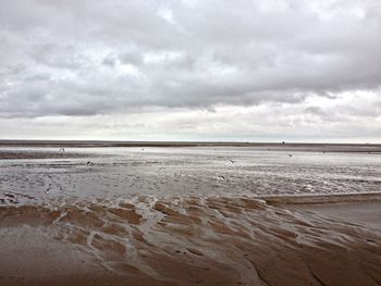 Scenic view of beach against cloudy sky