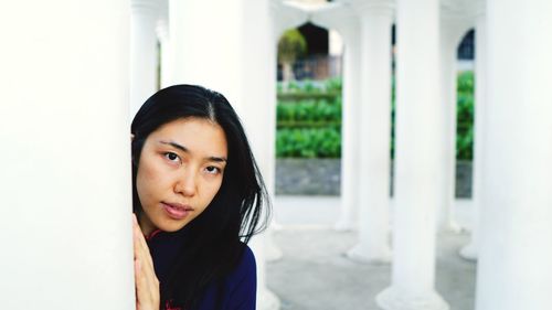 Portrait of woman standing by pillar