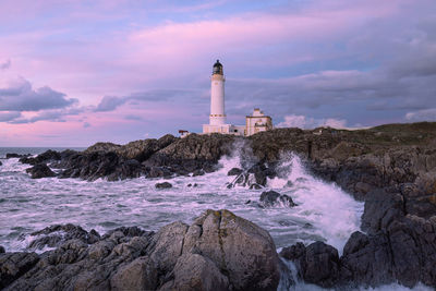 Lighthouse by sea against sky