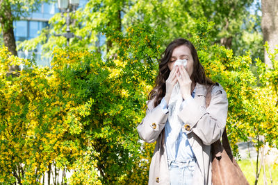 Young woman standing against trees