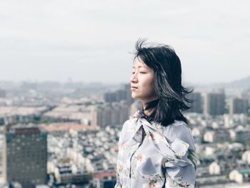 Young woman standing against cityscape in city