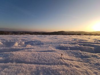 Scenic view of snow covered land against sky during sunset