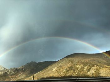 Scenic view of rainbow over mountains against sky