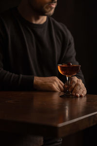 Midsection of man holding wineglass on table