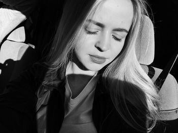 Close-up of young woman with eyes closed sitting in car