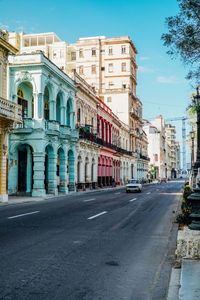 Road by buildings against sky in city