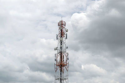 Low angle view of communications tower against cloudy sky