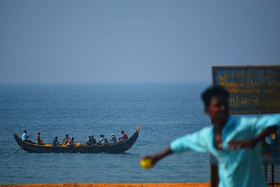 People on sea against clear sky