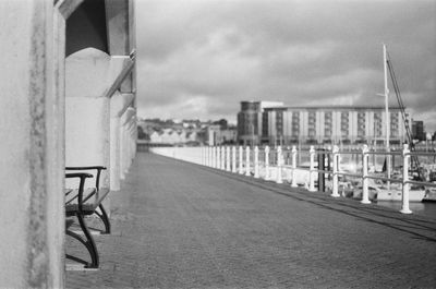 Empty chair by sea against buildings