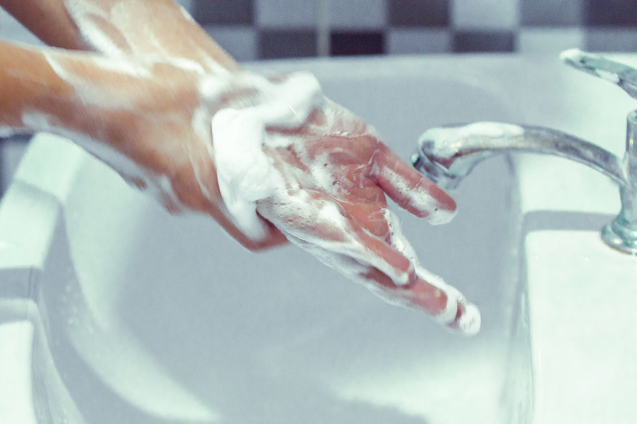 CLOSE-UP OF HAND TOUCHING WATER IN BATHROOM