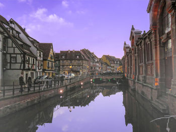 Bridge over canal amidst buildings against sky in city