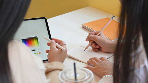 Midsection of woman using mobile phone while sitting on table