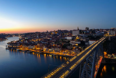 High angle view of illuminated city by river against sky