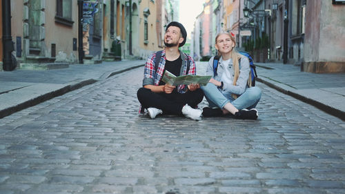 Young couple sitting on street in city