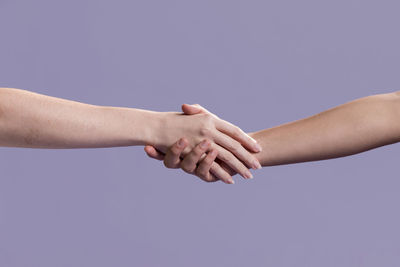 Midsection of couple holding hands against blue background