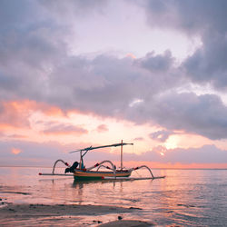 Fishing boat in sea against sky during sunset