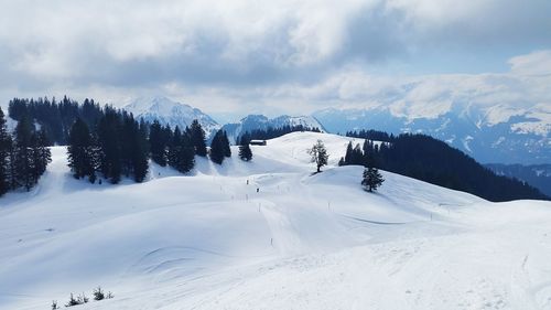 Scenic view of snow covered mountains against cloudy sky