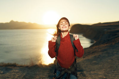 Portrait of smiling woman standing on land against sky during sunset