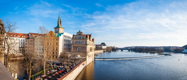 Bridge over river by buildings in city against sky