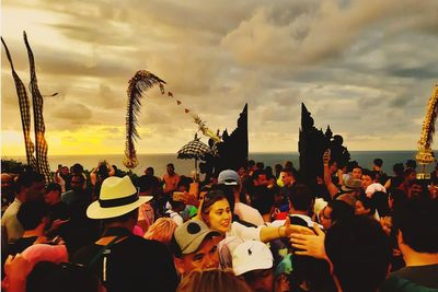 Group of people in amusement park against sky during sunset