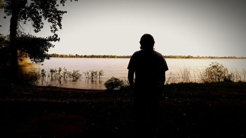 People standing by lake against clear sky