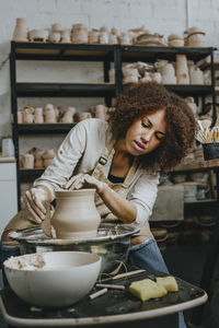 Young craftswoman molding pot shape on pottery wheel