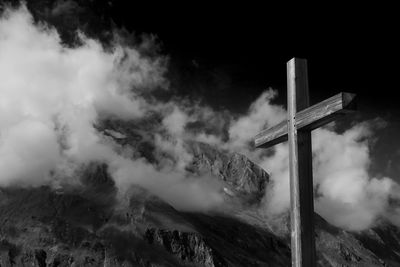 Plain wooden summit cross jesus christ crucifixion with alps mountain ranges and thick clouds sky.