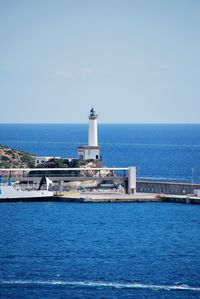 Lighthouse by sea against sky