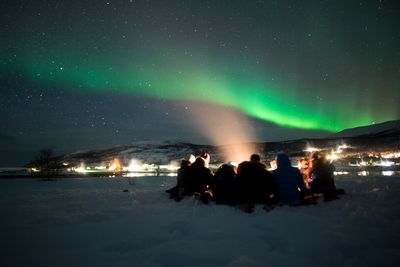 People on snow covered mountain against sky at night