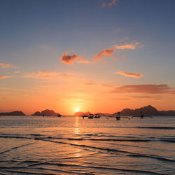 Outrigger boats on sea against sky during sunset