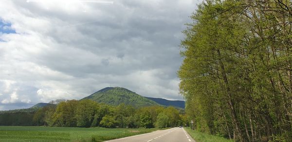 Road by trees against sky