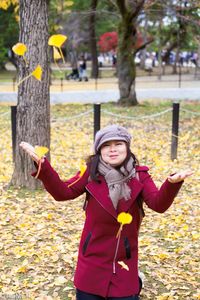 Portrait of woman throwing leaves in park