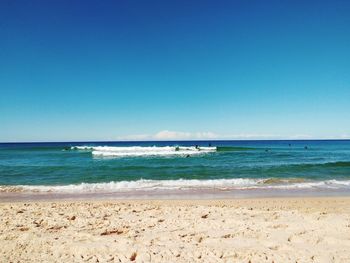 Scenic view of beach against clear blue sky