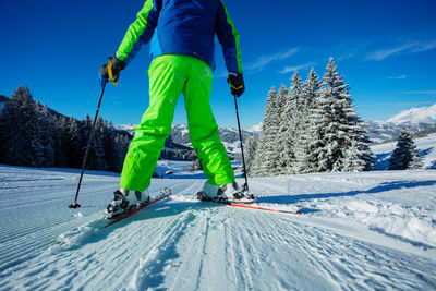 Low section of man skiing on snow covered landscape