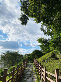 Footpath by railing against sky