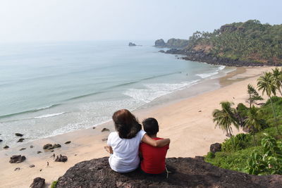 Rear view of woman sitting on beach