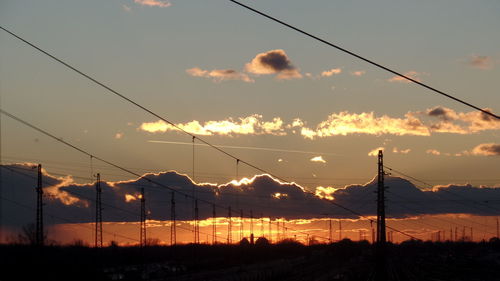 Silhouette electricity pylon against sky during sunset