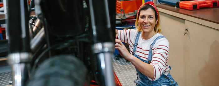 Portrait of mechanic woman repairing motorcycle on factory