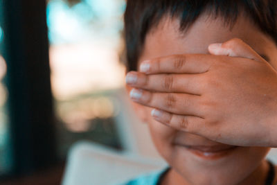 Close-up of boy covering eyes