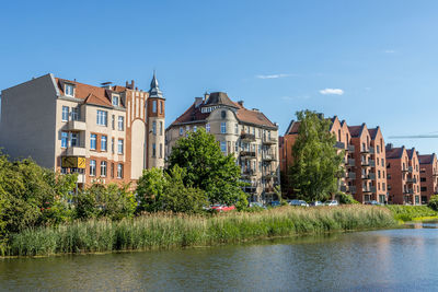 Buildings by the river against blue sky